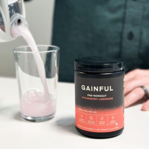 person pouring gainful pre workout from a shaker into a cup