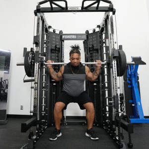 a person squatting in Force USA's G15 all-in-one trainer in a gym