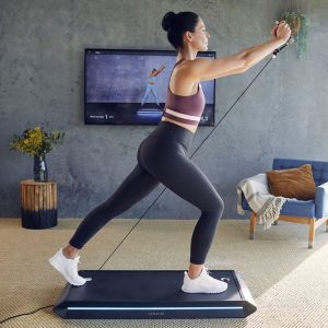 woman in living room using vitruvian form trainer in front of tv for workout