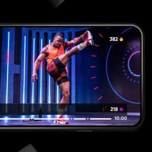 viewing the Fiit workout app on a phone screen, with a male workout instructor performing a high kick
