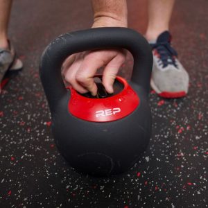 a man adjusting the weight on a rep fitness adjustable kettlebell