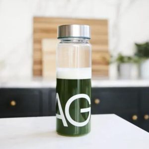 a mixed up shaker containing AG1 greens powder ready to drink sitting on a kitchen counter