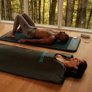 a man and a woman lie on the floor and try out the higher dose of infrared sauna blanket