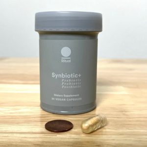 bottle of ritual synbiotic with capsule next to penny for size comparison
