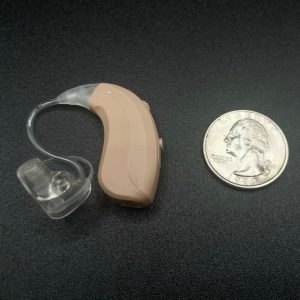 the mdhearing volt rechargeable hearing aid on a table next to a quarter for size comparison