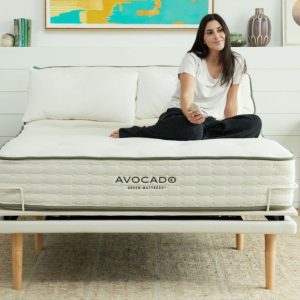 A girl sits on top of an Avocado Eco Pro-Adjustable Base bed