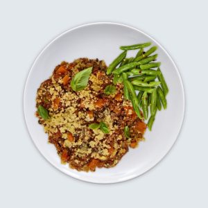 Splendid Spoon meal featuring a healthy dish of vegetable couscous and green beans, garnished with fresh basil leaves, presented on a white plate for a nutritious and convenient meal delivery service.