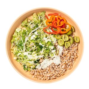 a meal from Purple Carrot with sliced red bell peppers, halved green olives, broccoli, shredded brussel sprouts, and barley with a white dressing