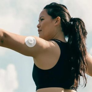 a woman doing a stretch outside while wearing her nutrisense glucose monitor