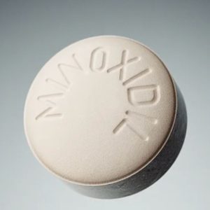 white circular pill with minoxidil written on it