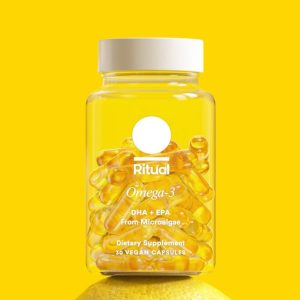 A bright yellow-themed bottle of Ritual Omega-3 dietary supplement, containing DHA and EPA derived from microalgae, presented with 30 vegan capsules inside.